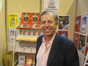 Bernard Maris, économiste de Charlie Hebdo, souriant devant un stand de dédicace de Cabu